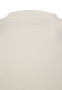 Polo bianca in cotone con finitura strutturata, con un logo a rilievo sottile sul retro del colletto. Design del colletto classico, stile minimalista.