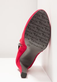 Rote Wildleder-High-Heels mit spitzer Zehe, ausgestattet mit einem seitlichen Reißverschluss und einer schwarzen Sohle, die mit "tamaris" geprägt ist. Größe 37 angegeben.