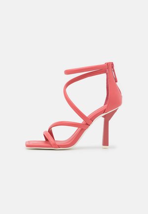 Różowe sandały na wysokim obcasie z wieloma krzyżującymi się paskami, kwadratowym noskiem i geometrycznym blokowym obcasem. Gładka tekstura z zamkiem błyskawicznym z tyłu.