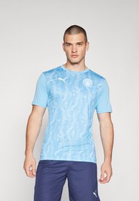 T-shirt de sport bleu clair à manches courtes, présentant un motif texturé de chiffres et un logo blanc sur la poitrine gauche.