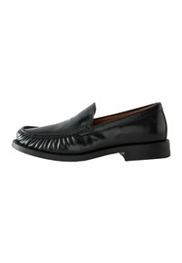 Mocasines de cuero negro con detalles de costura alrededor de la parte superior, punta redondeada y un tacón bajo y texturizado.