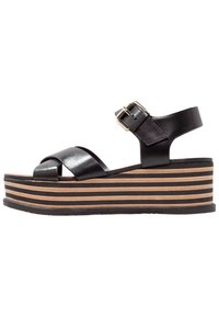 Black leather platform sandals with a crisscross strap design, a buckle closure, and a striped wooden wedge heel.