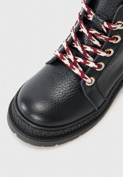 Svart läderstövel med texturerad yta, utrustad med bordeaux- och vita flätade snören, guldfärgade öglor och en mönstrad gummisula.