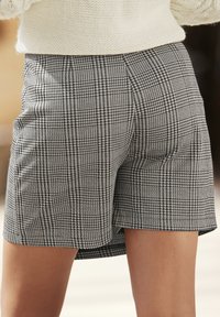 Zwart-wit geruite shorts met een getailleerde pasvorm, gladde stof en een licht uitlopende zoom, met een klassiek patroon ontwerp.
