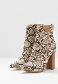 Stivaletti con tacco alto in finta pelle di serpente beige e marrone, dotati di cerniera laterale e tacco quadrato strutturato.