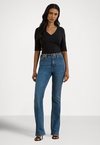 Calças de ganga azul de cintura alta com corte de perna reta, tecido texturizado, cinto embelezado e um top justo preto com decote em V.