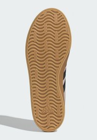 Sole obuvi Adidas s texturovaným gumovým materiálem a vlnitými vzory, černými a růžovými akcenty a logem vyraženým poblíž paty.