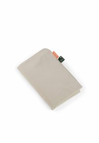 Sacchetto di tessuto beige con bordi arrotondati e due etichette piccole, una arancione con la dicitura "100% amichevole" e una nera con testo bianco.