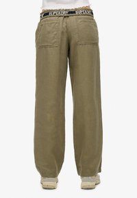 Pantalons larges en vert olive, en tissu texturé, avec une taille élastique affichant le logo "SUPERDRY" et deux poches arrières.