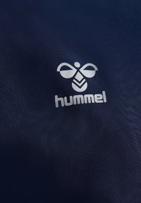 Marinefarget stoff har en hvit logo med en stilisert bie og ordet "hummel" under, som skaper et strømlinjeformet, moderne design.