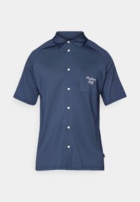 Marineblå polo skjorte med teksturert stoff, korte ermer, knappestolpe foran, og en brystlomme som har "Malborn Golf" broderi i hvitt.