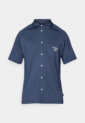 Marineblå polo skjorte med teksturert stoff, korte ermer, knappestolpe foran, og en brystlomme som har "Malborn Golf" broderi i hvitt.