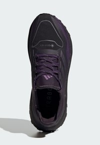 Baskets de sport violettes avec une tige texturée, un orteil renforcé, une semelle rembourrée et des lacets violets. Présente un logo sur la langue et le côté.