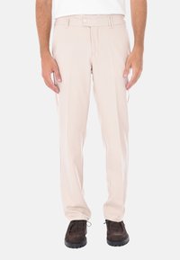 Pantaloni beige su misura in tessuto liscio, con una vestibilità dritta, doppie pince e chiusura con bottone. Indossati con scarpe marroni scure.