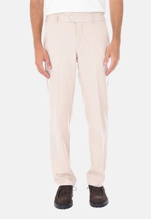 Pantaloni beige su misura in tessuto liscio, con una vestibilità dritta, doppie pince e chiusura con bottone. Indossati con scarpe marroni scure.