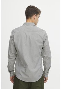 Gestreept overhemd met knoopsluiting in een lichte stof, met smalle verticale strepen in donkere en lichte kleuren, voorzien van een puntige kraag en knoopmanchetten.