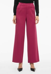 Pantalon à jambes larges de couleur magenta vif, en tissu lisse. Il présente une taille haute, un design structuré, et des poches avant.