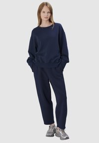 Marineblauwe katoenen sweatshirt met een ontspannen pasvorm, hoge hals en geribbelde manchetten, gecombineerd met bijpassende broek met een tailleband met trekkoord.