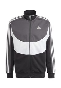 Giacca nera e grigia con zip, con accenti bianchi, caratterizzata da un alto colletto, tre strisce bianche su ciascun maniche e un logo Adidas sul petto.