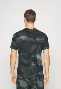 Svart och grå mönstrad t-shirt med kort ärm och rund halsringning, med en mjuk tygkvalitet och abstrakt penseldesign.