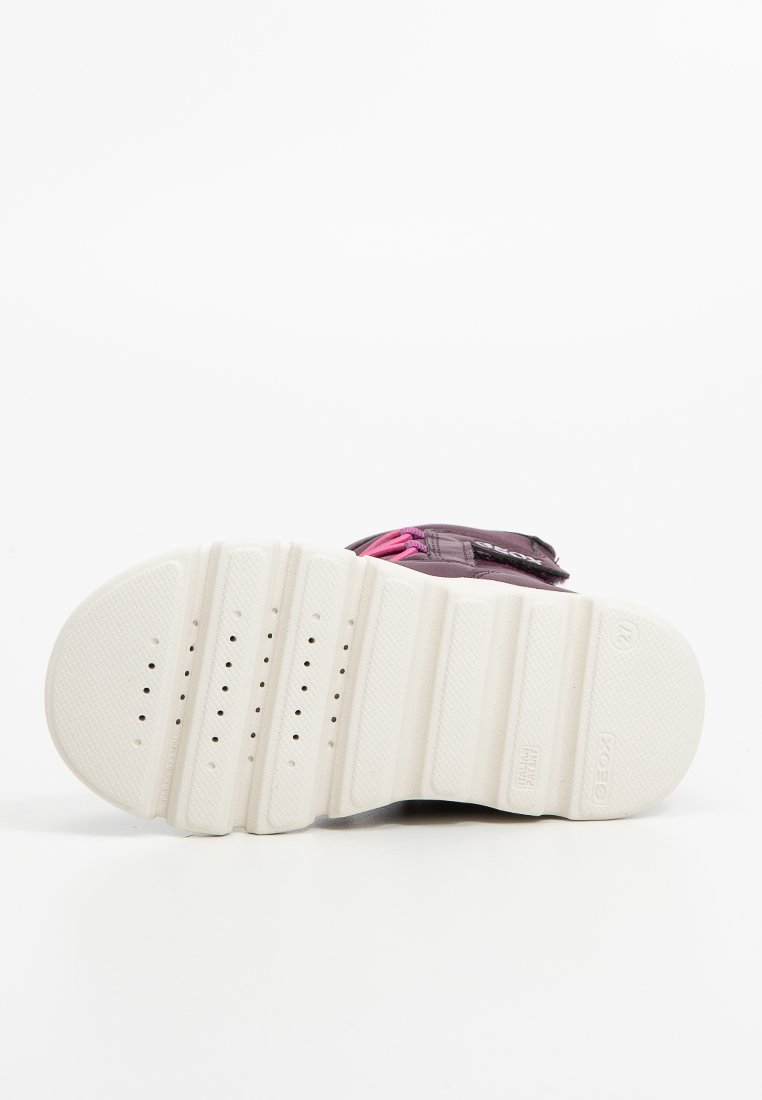 Dziecięce sneakersy z fioletową cholewką, różowymi akcentami i białą gumową podeszwą z wieloma rowkami antypoślizgowymi oraz otworami wentylacyjnymi.