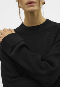 Schwarzer gestrickter Pullover mit geripptem Rundhalsausschnitt und übergroßen Ärmeln, aus einem weichen Material und in lässiger Passform.