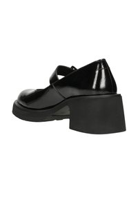 Czarne lakierowane buty typu Mary Jane z grubym obcasem i pojedynczym paskiem na wierzchu, widok z tyłu pod kątem.