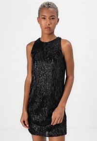 Schwarzes ärmelloses Kleid mit einem strukturierten Fransen-Design, das glänzende Akzente und einen geraden Schnitt aufweist und eine minimalistische Silhouette schafft.