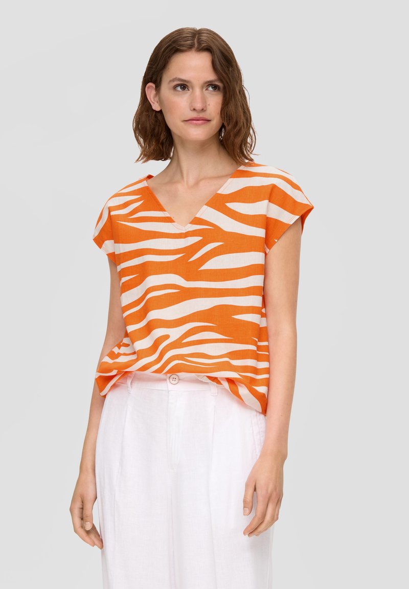 Oranje en crèmekleurige gestreepte blouse met een V-hals en kapmouwen, gemaakt van lichte stof, gecombineerd met witte linnen broek.