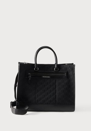 Black Michael Kors tote bag with embossed logo pattern, top handles, front zip pocket, and adjustable shoulder strap on white background.