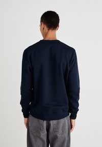 Sudadera de cuello redondo en azul marino, hecha de una tela suave, con puños y dobladillo de canalé, con un ajuste holgado y sin logos ni patrones visibles.