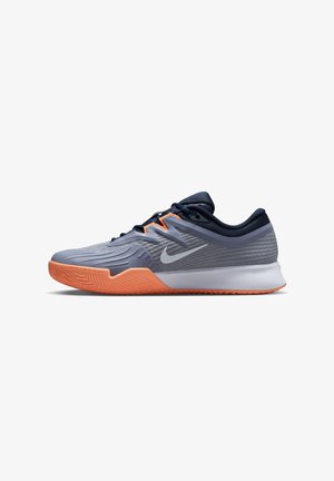 Nike Sportschuh mit einem grauen Mesh-Obermaterial, orangefarbener Gummisohle, schlanker Gestaltung und strukturierten Akzenten sowie einem markanten Logo.