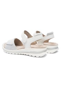 White open-toe sandals with adjustable straps, cushioned footbed, and ridged white soles, shown from back and side angles.