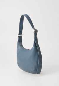 Bolso de mano de cuero azul con una forma curva y estructurada. Presenta una correa plana y costuras sutiles a lo largo del costado, con cierre de cremallera en la parte superior.