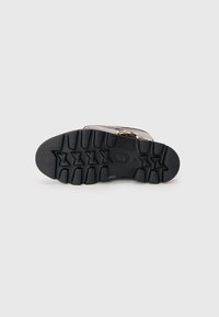Sole de pantof din cauciuc negru cu un model robust de profil, având striații adânci și accente în formă de stea, conceput pentru aderență și durabilitate.