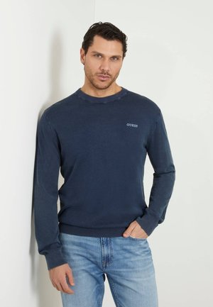 Maglione girocollo blu navy in tessuto morbido con maniche lunghe e polsini a costine, dotato di un piccolo logo ricamato sul petto.