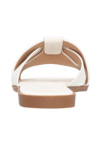 Sandalias de cuero blanco con un diseño de respaldo abierto y correas curvadas, y una suela de goma marrón y una plantilla texturizada para mayor comodidad.