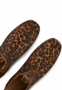Stivali alla caviglia a stampa leopardata con una morbida texture scamosciata, caratterizzati da una punta arrotondata e pannelli elastici laterali per una facile calzata. Colori marrone e nero.