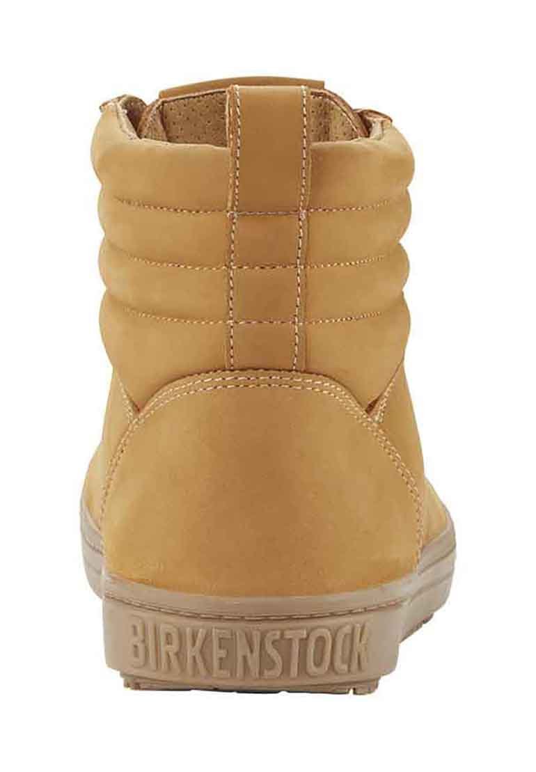 Tan leather ankle boot with a padded collar, subtle stitching details, and a textured rubber sole featuring the brand name “Birkenstock.”