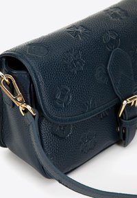 Granatowa torebka crossbody z teksturowanej skóry, z ozdobnymi elementami w kolorze złotym, wyposażona w wytłoczone logo oraz magnetyczne zapięcie klapy.