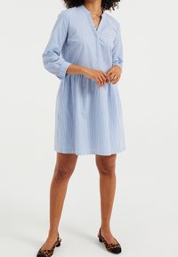 Sininen ja valkoinen raidallinen mekko, jossa on kaulus, kolme neljäsosaa hihapituudesta ja kapea vyötärö. Yhdistetty leopardikuvioisiin ballerinoihin. Minimalistinen muotoilu.