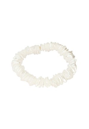 Bracelet extensible composé de perles blanches de forme irrégulière, disposées étroitement en un motif circulaire sur fond blanc.