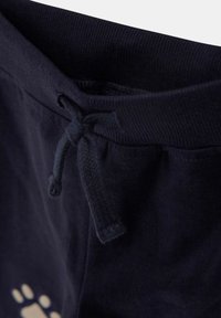 Marineblå joggebukser med elastisk midje og knyttet snor, og delvis lyse fargede labbtrykkdesign på myk stoff.