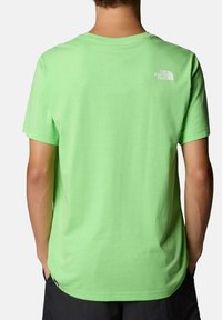Camiseta de algodón verde con cuello redondo, mangas cortas y un pequeño logo blanco en la parte superior de la espalda. Textura suave; corte relajado.