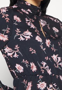 Floral-printed dress featuring a black background with pink and white flowers, high neckline, and gathered waist for a fitted silhouette.