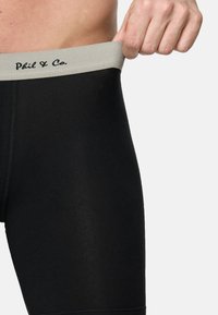 Svarta stretchshorts med en grå elastisk midjeband där "Phil & Co." är broderat i svart. Slät textur, kroppsnära design.