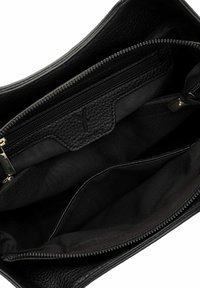 Interno di una borsa a mano in pelle nera con finitura testurizzata, dotata di una tasca con zip e rivestimento in tessuto. Diverse scomparti per l'organizzazione.