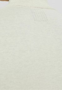 Helles beige Sweatshirt mit hohem Kragen und gerippter Textur, mit dezentem Logo-Detailing auf der Rückseite in der Nähe des Kragens.