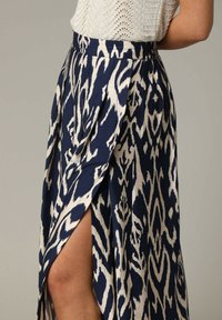 Jupe fluide navy avec un motif abstrait crème, dotée d'une fente latérale haute et d'une taille ajustée, fabriquée en tissu léger.