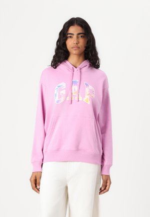Rosa hettegenser laget av mykt stoff, med en frontlomme og hettetråder. Fronten har et flerfarget "GAP"-logo.